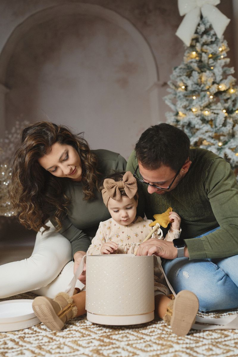 Mini sessione di Natale in studio a Siracusa: famiglia con il pacco regalo davanti all'albero