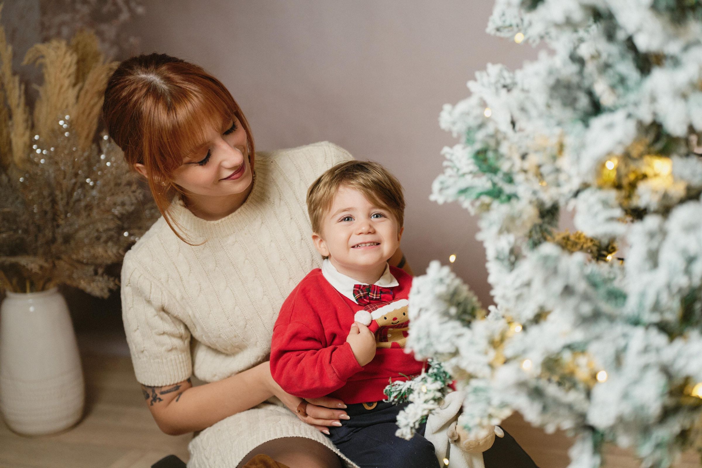 Mini sessione di Natale in studio a Siracusa: mamma e bambino accanto all'albero innevato