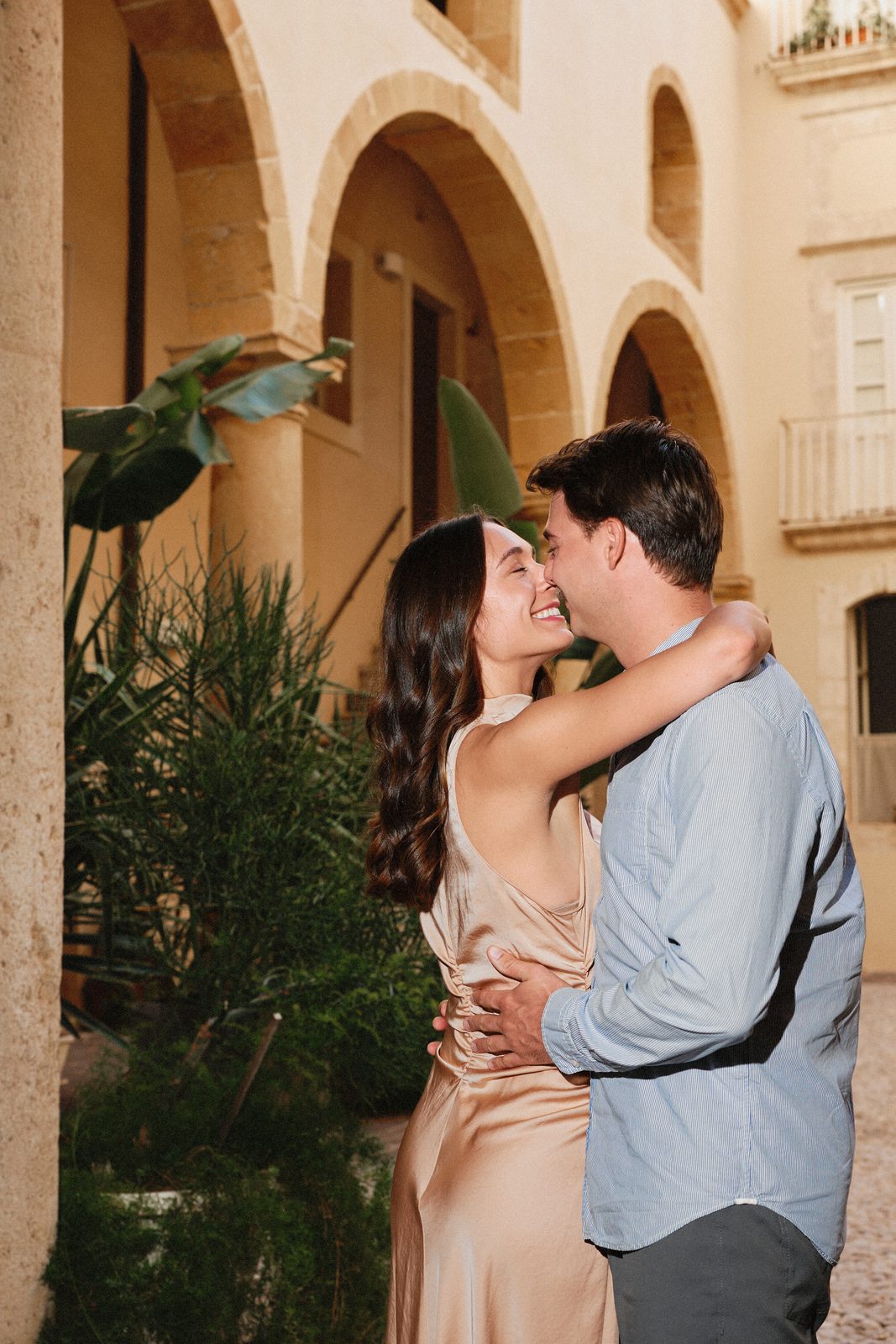 Couple embracing among the plants of a courtyard in Ortigia