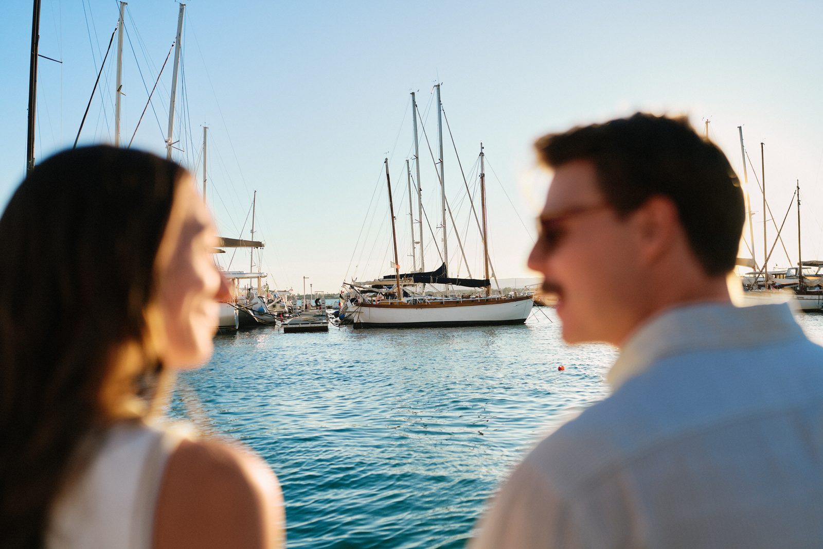 Couple at the Marina of Ortigia, sailboats behind them