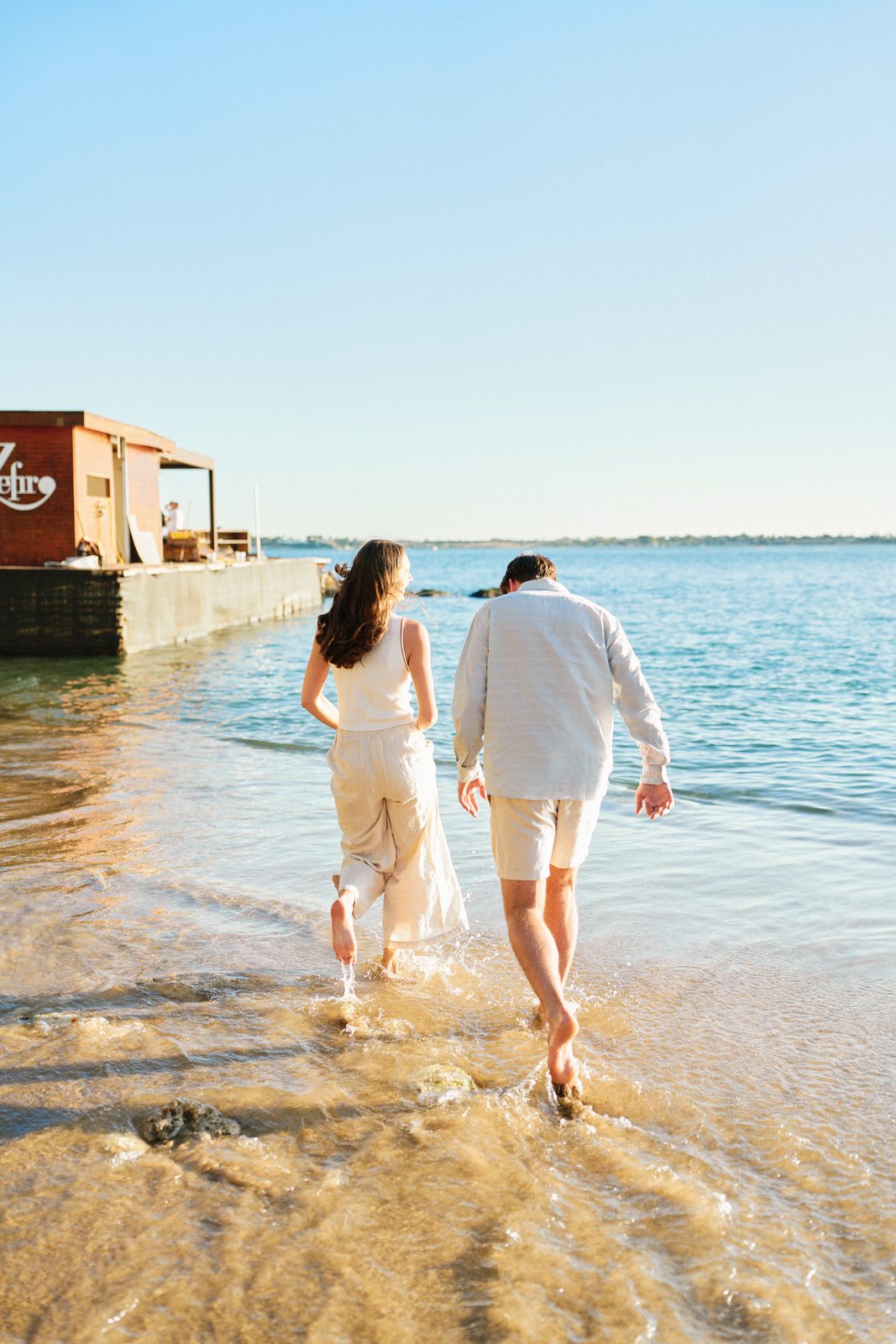 Couple walking into the sea on a little beach in Ortigia