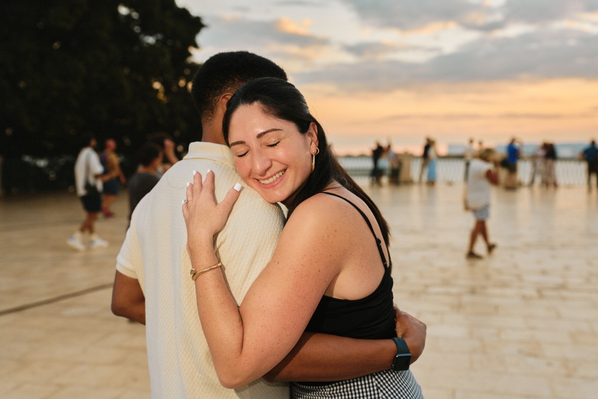 Engaged couple hugging at sunset on the Ortigia seafront, Syracuse