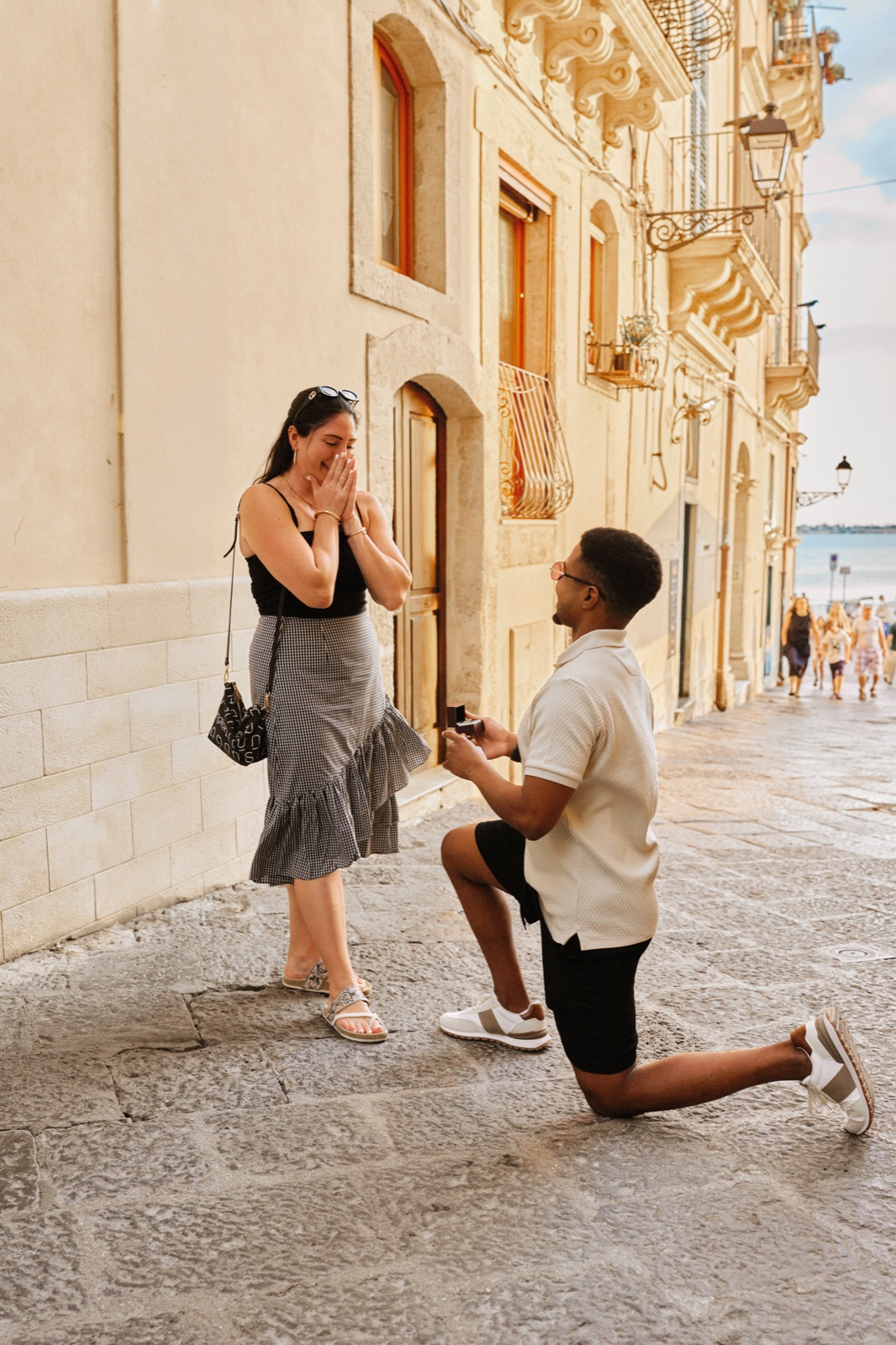 Überraschungsantrag in Ortigia: Er kniet mit dem Ring in der Via Pompeo Picherali, Syrakus, am Ende der Straße das Meer