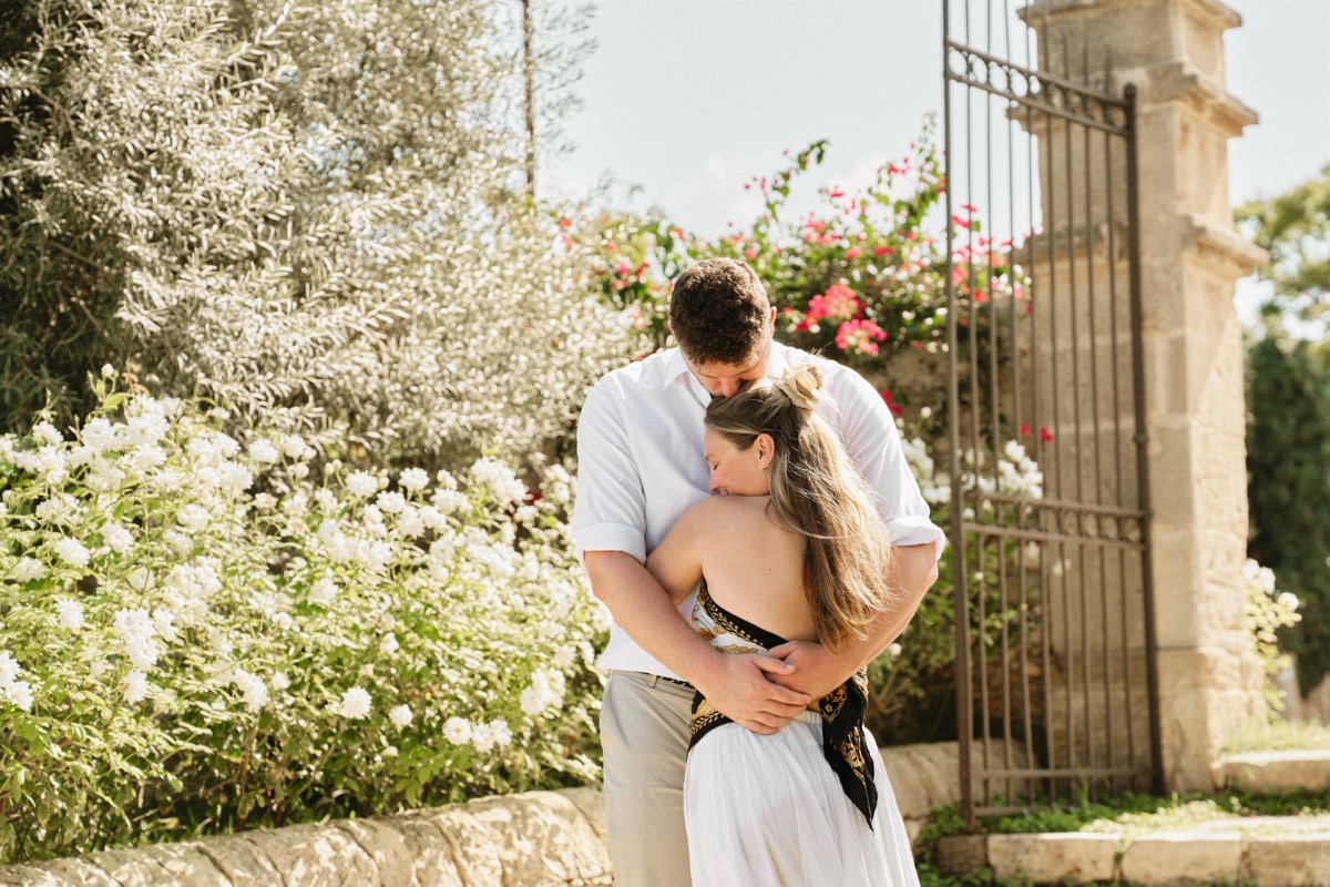 Hug by the iron gate of Cantine Pupillo, among white flowers