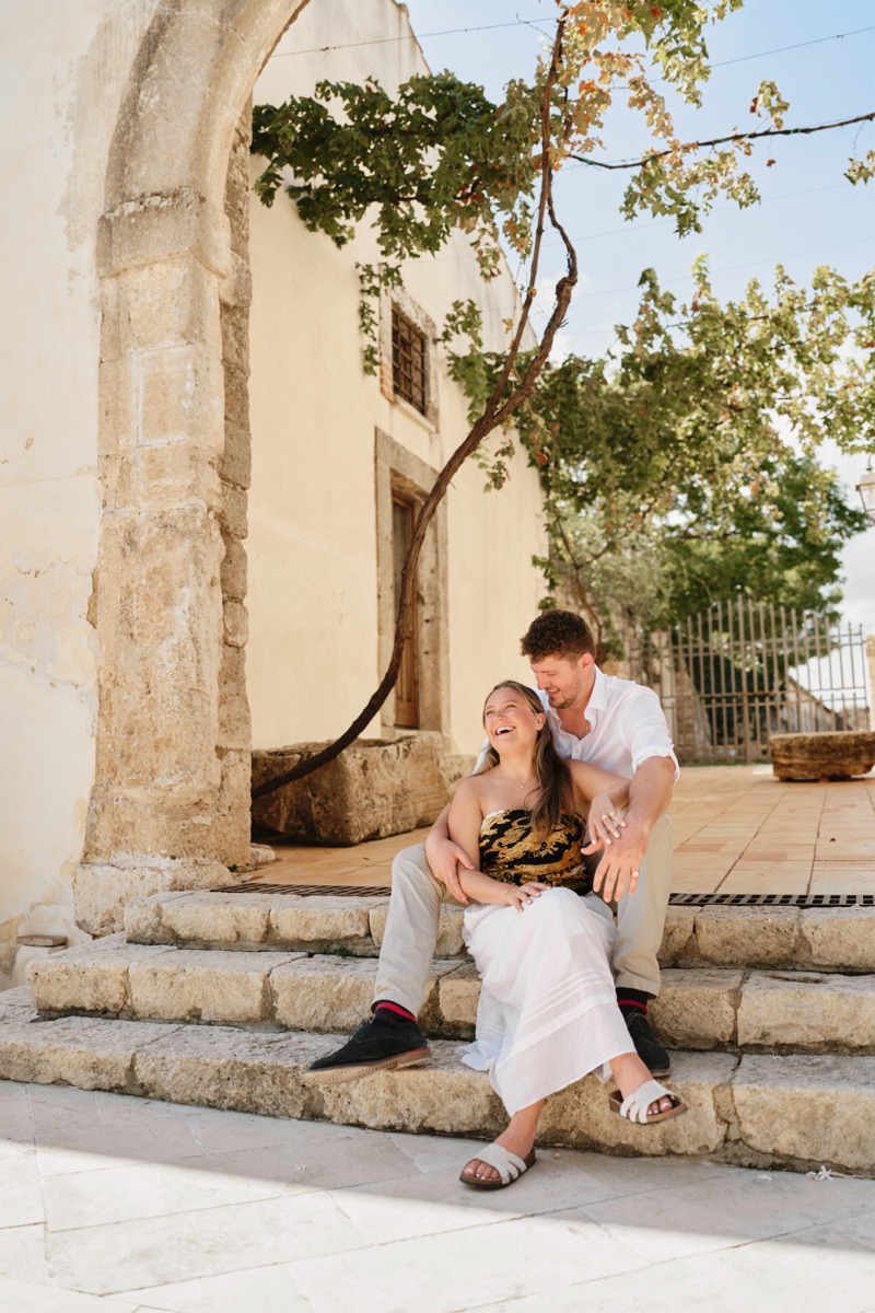 Couple laughing, sitting on the steps under the castle arch