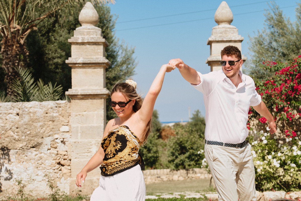 He twirls her by the gate pillars of the Cantine Pupillo estate